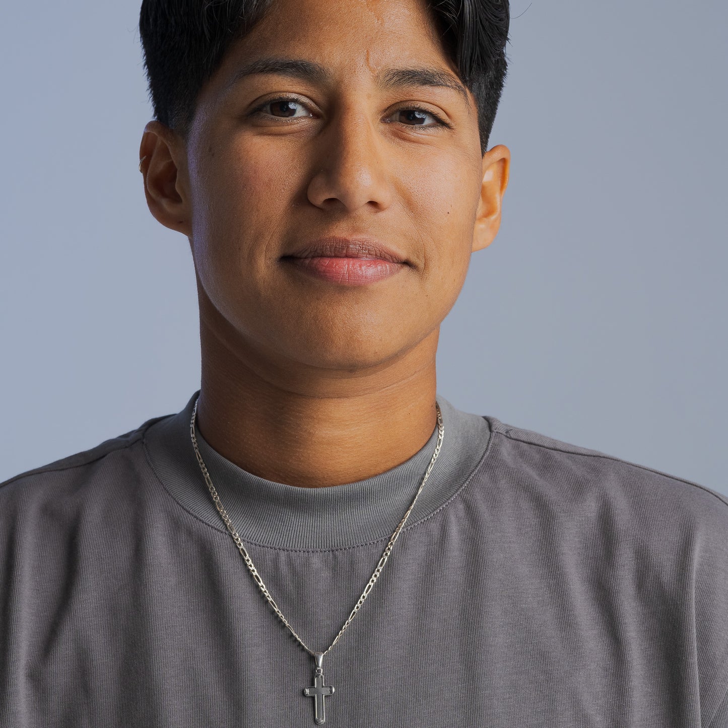 Person wearing a gray LGBTQIA+ inclusive t-shirt from Bro Code with a silver cross necklace