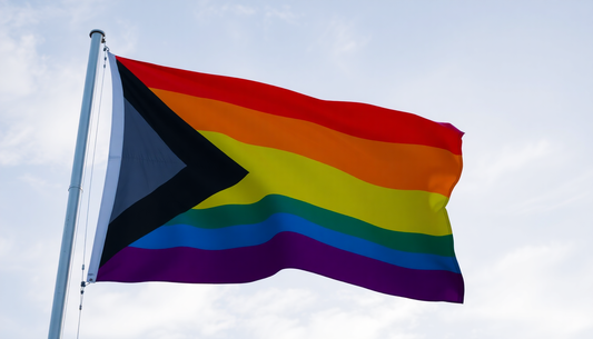 Pride flag waving against the sky representing the gender-affirming clothing importance in embracing identity