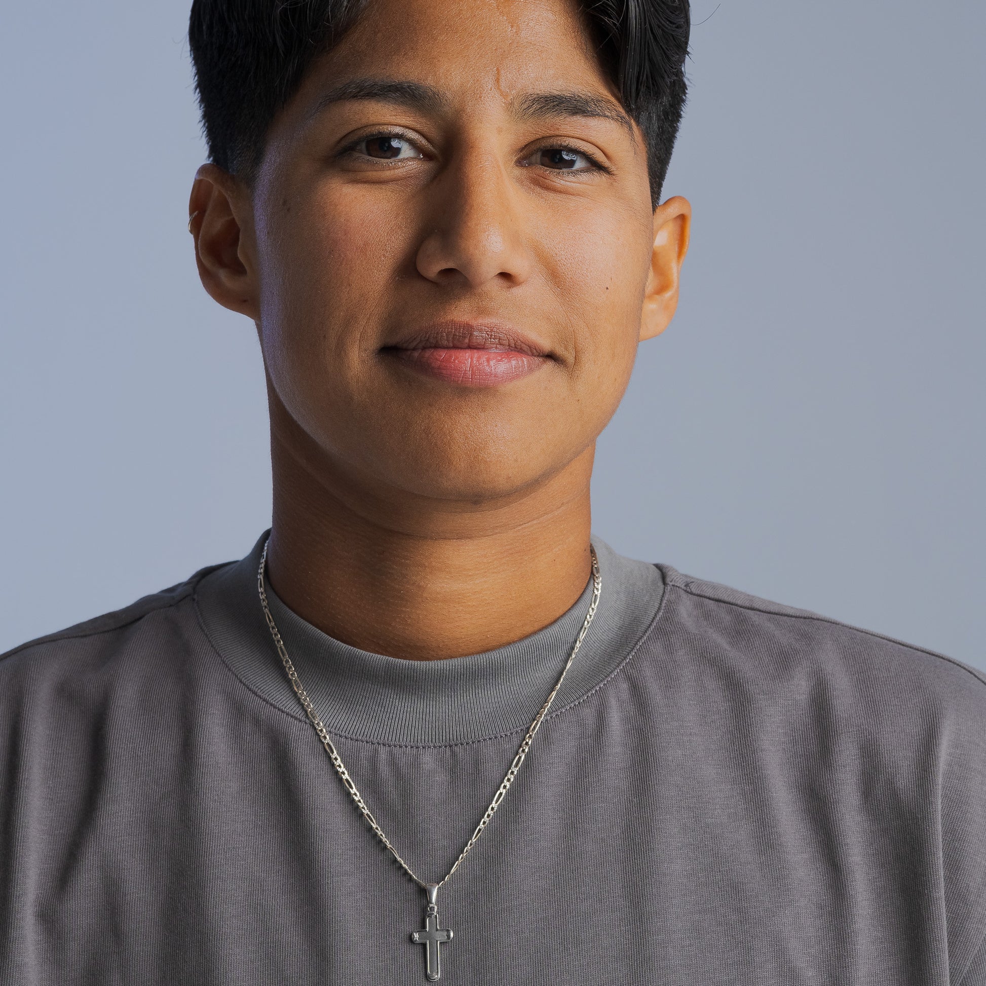 Person wearing a gray LGBTQIA+ inclusive t-shirt from Bro Code with a silver cross necklace